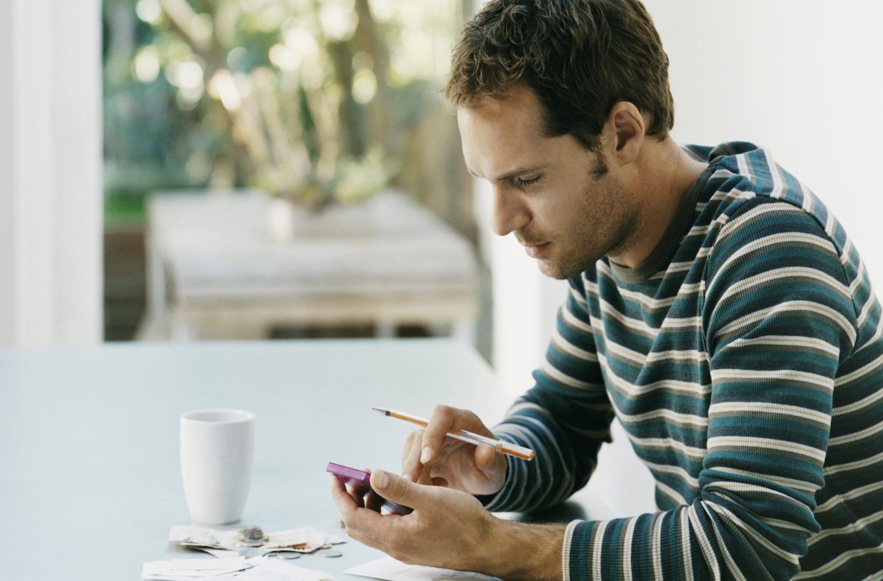 Man Sitting at a Table Using a Calculator