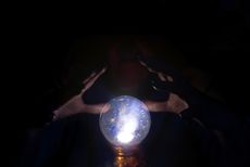 A unseen person's hands hover near a crystal ball