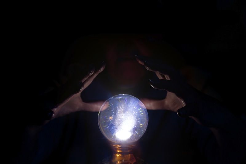 A unseen person&#039;s hands hover near a crystal ball