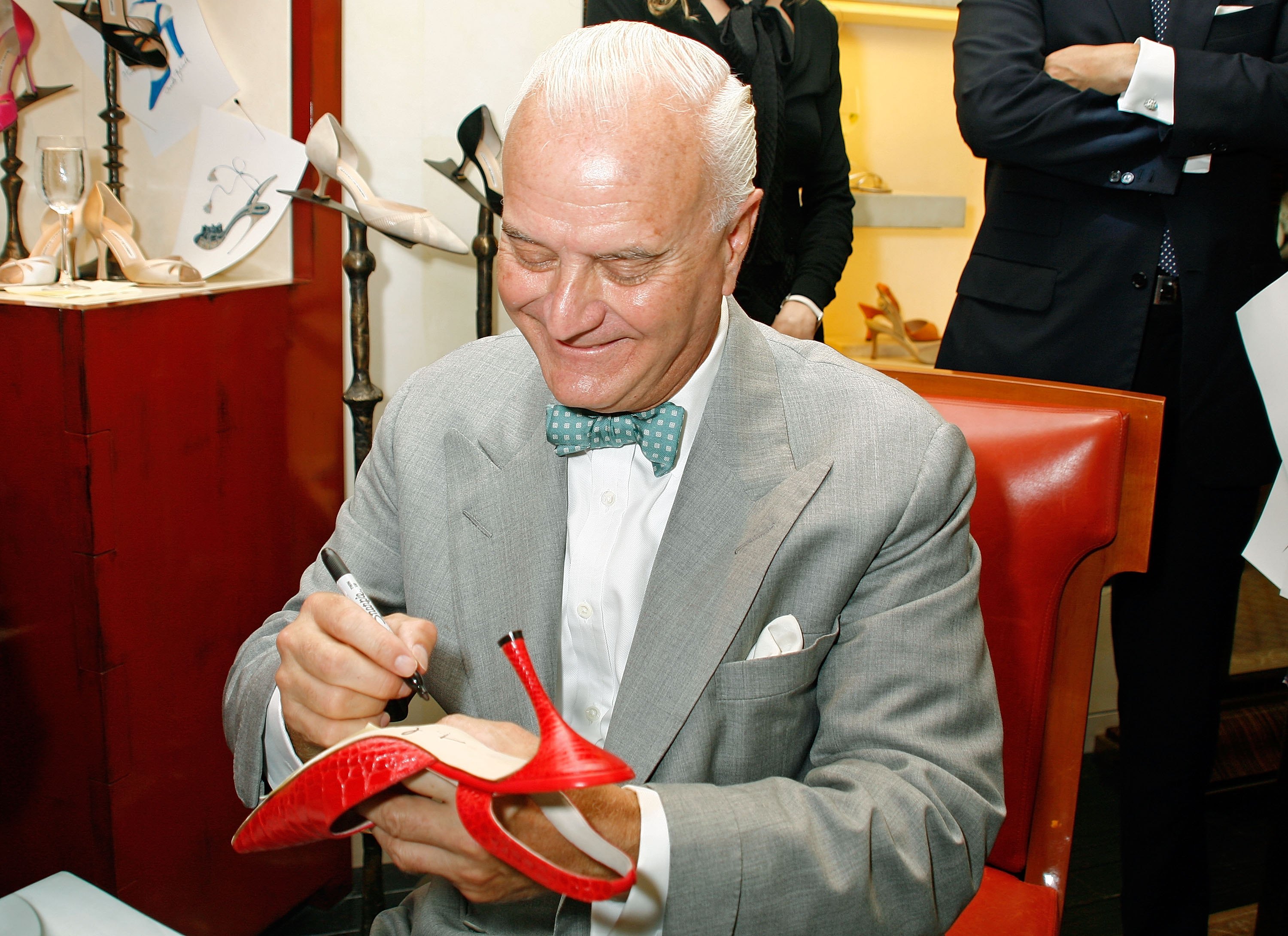 Manolo Blahnik signing the sole of a shoe
