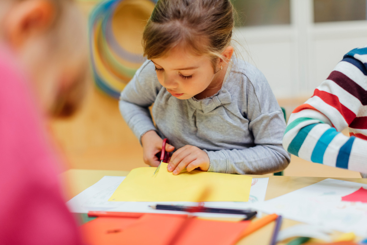 A child taking part in an arts & crafts activity using scissors to cut a piece of paper