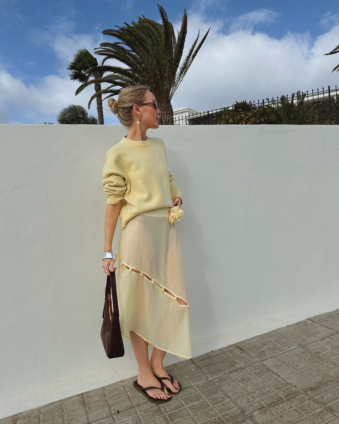 @chloekathbutler wears chocolate brown flip-flops with a butter yellow jumper, sheer skirt and chocolate brown shoulder bag
