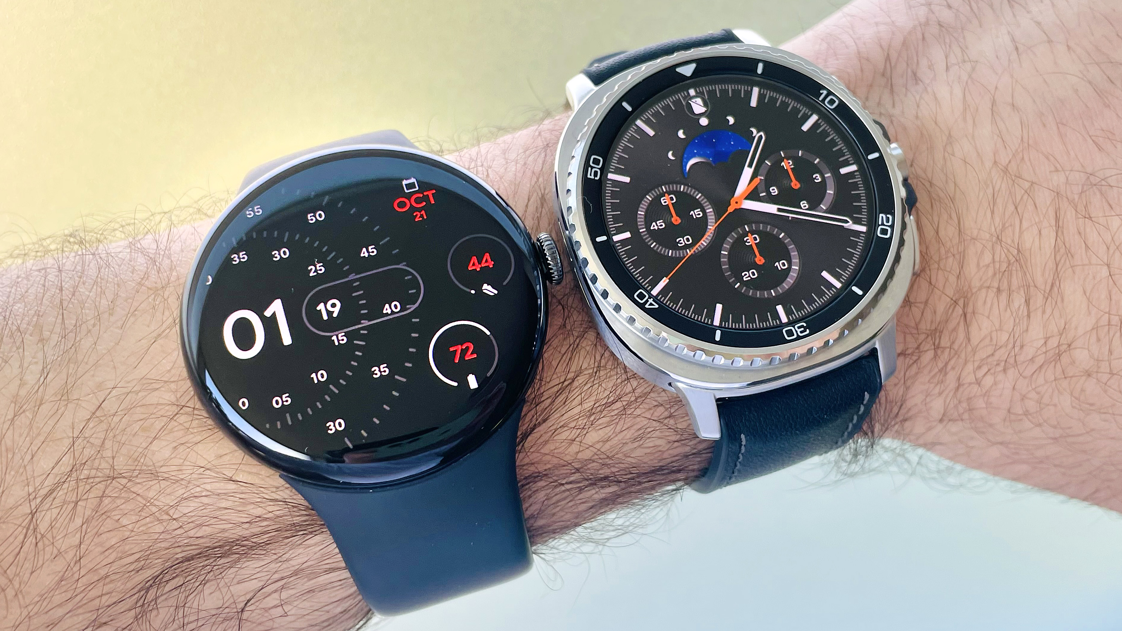 Close-up of the Google Pixel Watch 4 on a user&#039;s wrist next to the Samsung Galaxy Watch 8 Classic