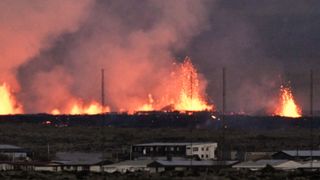 Lava explosions are seen near residential buildings in the southwestern Icelandic town of Grindavik after a volcanic eruption on January 14, 2024. 
