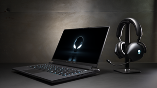 An alienware laptop next to alienware headphones on a stand