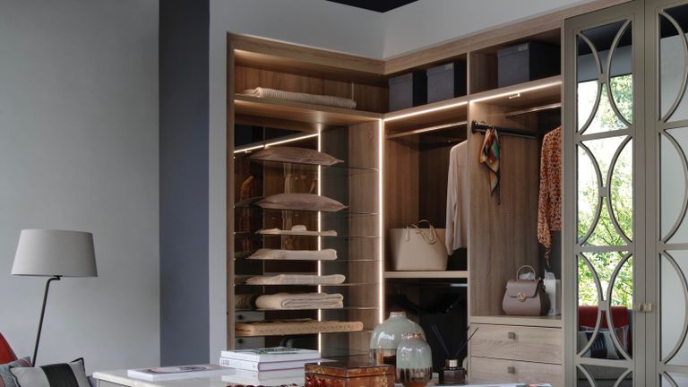 A small walk-in closet with LED lighting in the corner of a room