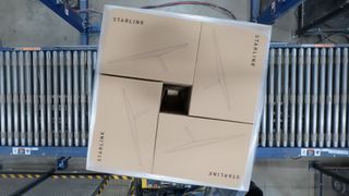 a cardboard box marked with the word "starlink" rolls across a conveyor belt in a factory