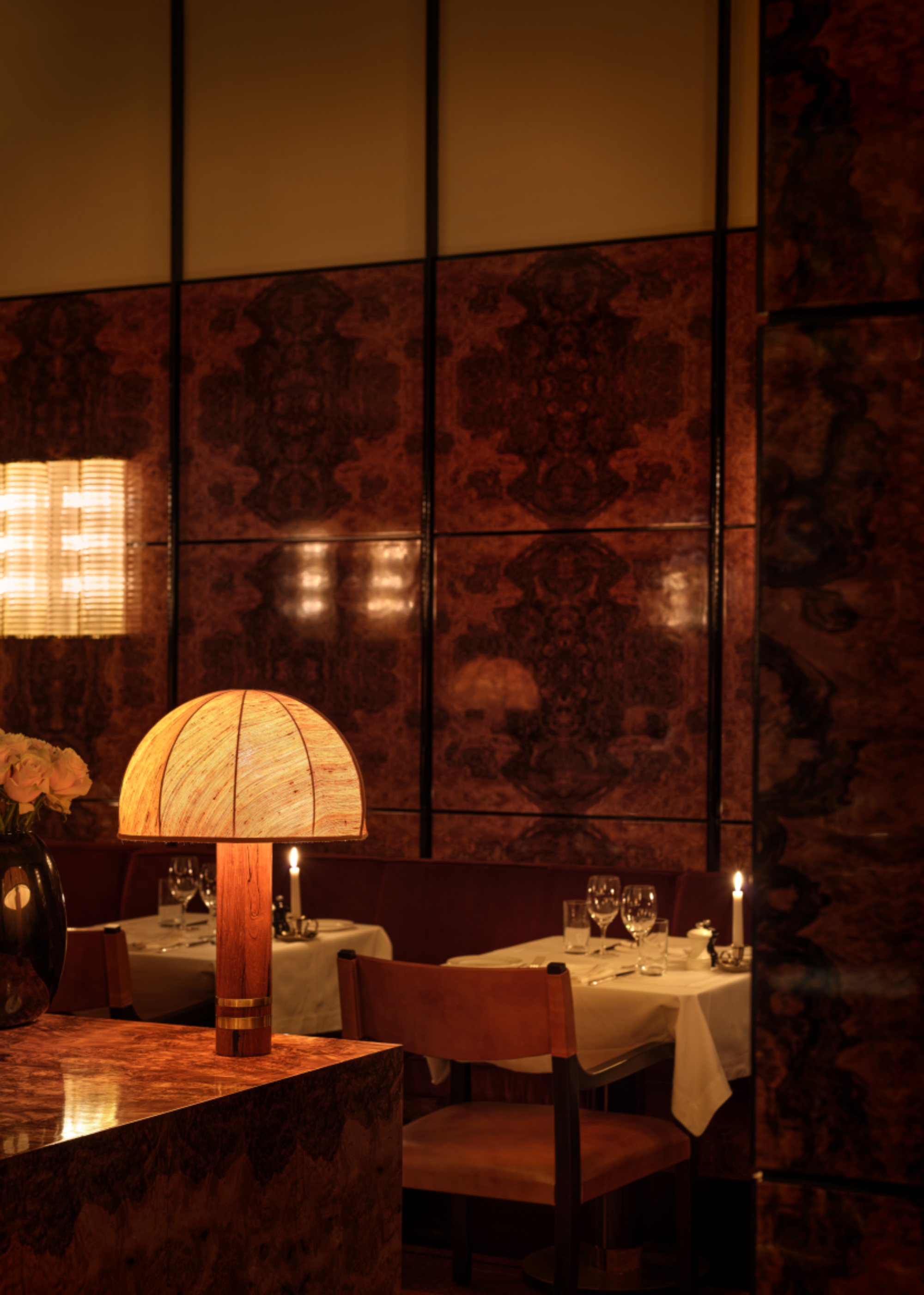 close up of burl wood panelling in a dimly lit dining room with candle-lit tables