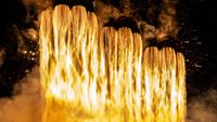 plumes of raging fire emanate from three parallel rings of nine cone-shaped rocket nozzles