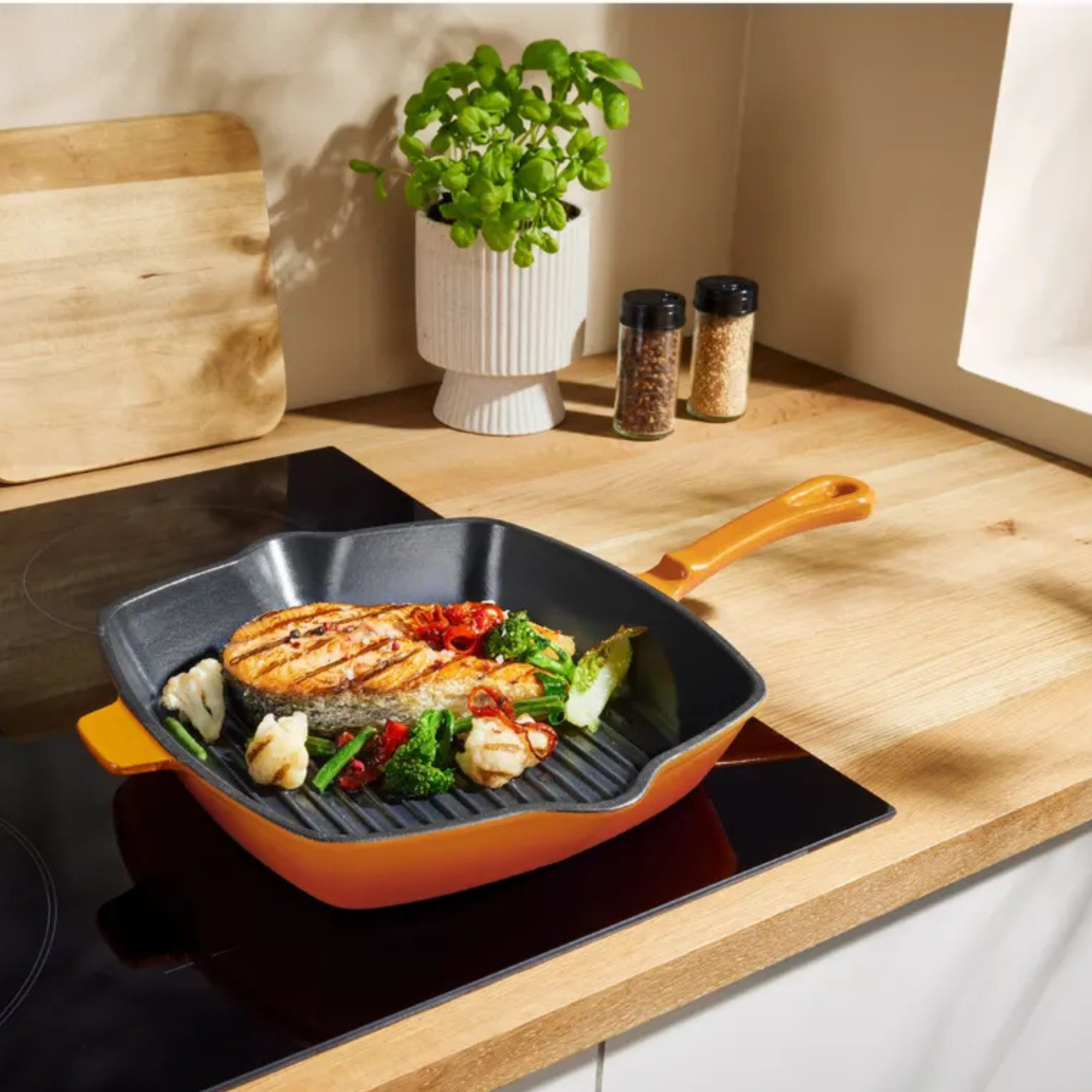 Silvercrest griddle pan in orange cooking chicken and vegetables on a hob.