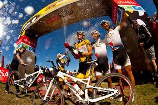 2012 Cape Epic Winners Burry Stander and Christoph Sauser of 36One-Songo-Specialized spray champaign as Max Knox and Kohei Yamamoto of Songo-Specialized look on