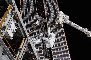NASA astronaut Tom Marshburn, riding at the end of the Canadarm2 robotic arm, works to replace a faulty S-band antenna outside of the International Space Station on Thursday, Dec. 2, 2021.