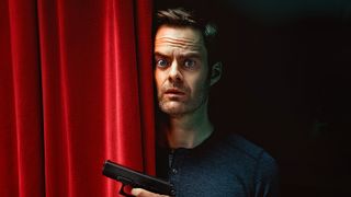 Bill Hader's Barry looks unsure as he stands next to a red curtain in the character's self-titled HBO TV show