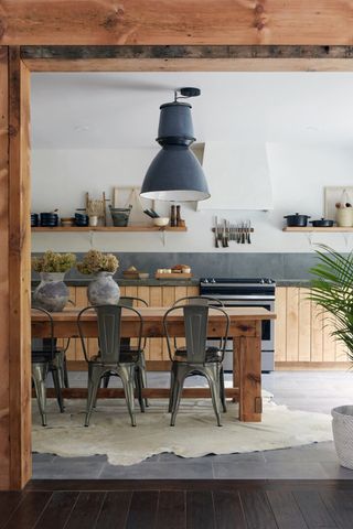 Rustic wooden farmhouse kitchen with slate grey cabinets and large industrial pendant light