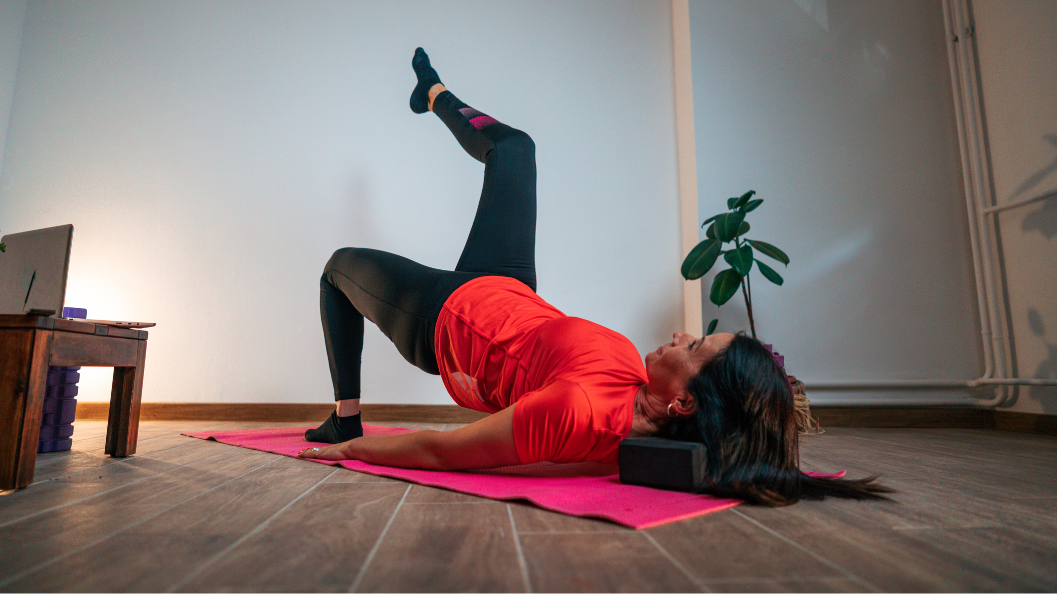 Woman performing the glute bridge march exercise in a domestic setting