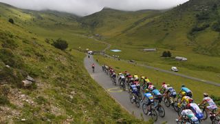 Et bilde sakset fra et tidligere Tour de France-arrangement, med et peloton kjørende i pittoreske fjellområder