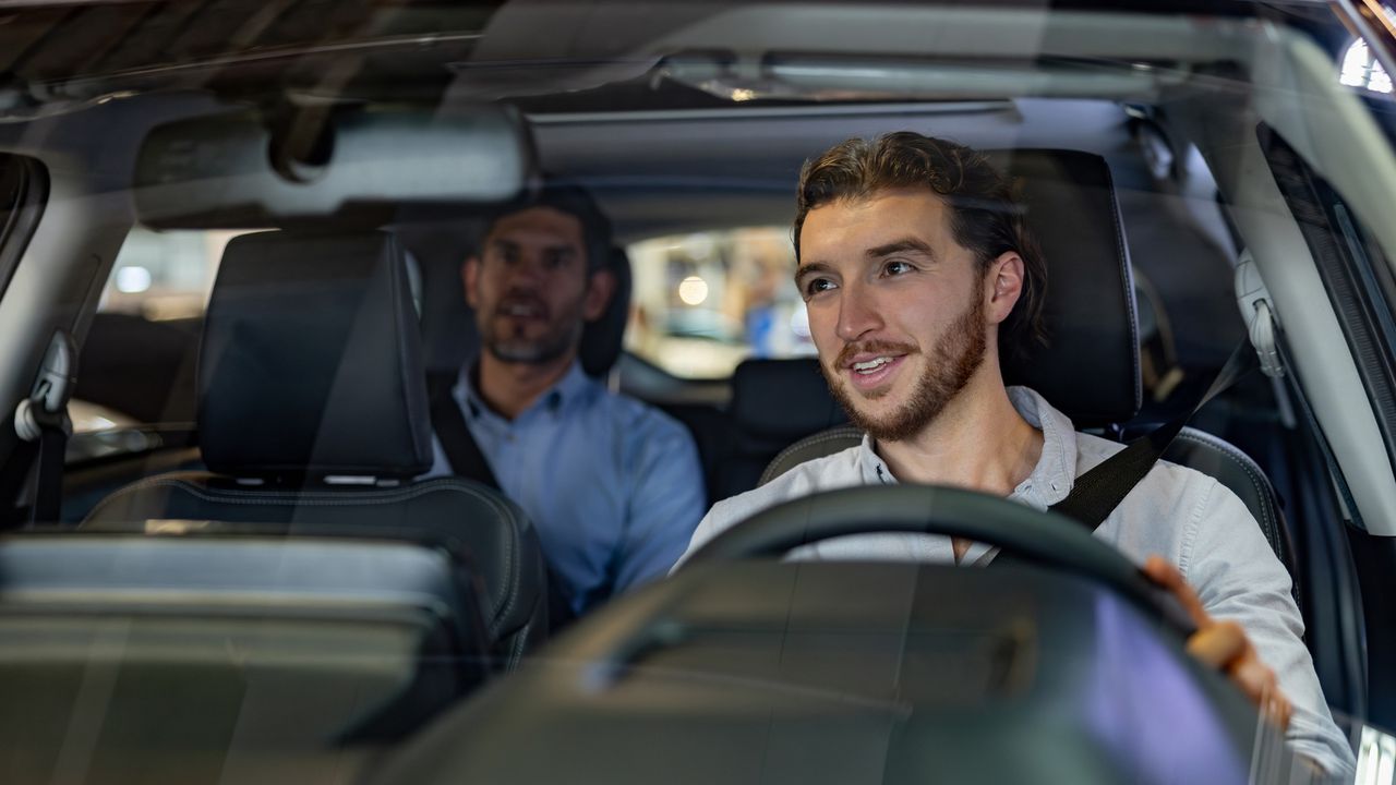 A ride-sharing driver talks with his client in the back seat of his car.