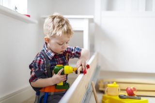 Young boy using toy power tool at home.