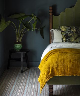 bedroom with striped carpet, dark green walls and yellow bedspread