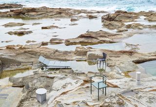 Sun lounger and coffee table on rocks by the sea