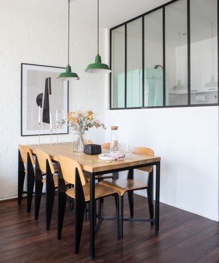 Dining area with wooden and steel table with 6 chairs on wooden floor with with windows facing the kitchen
