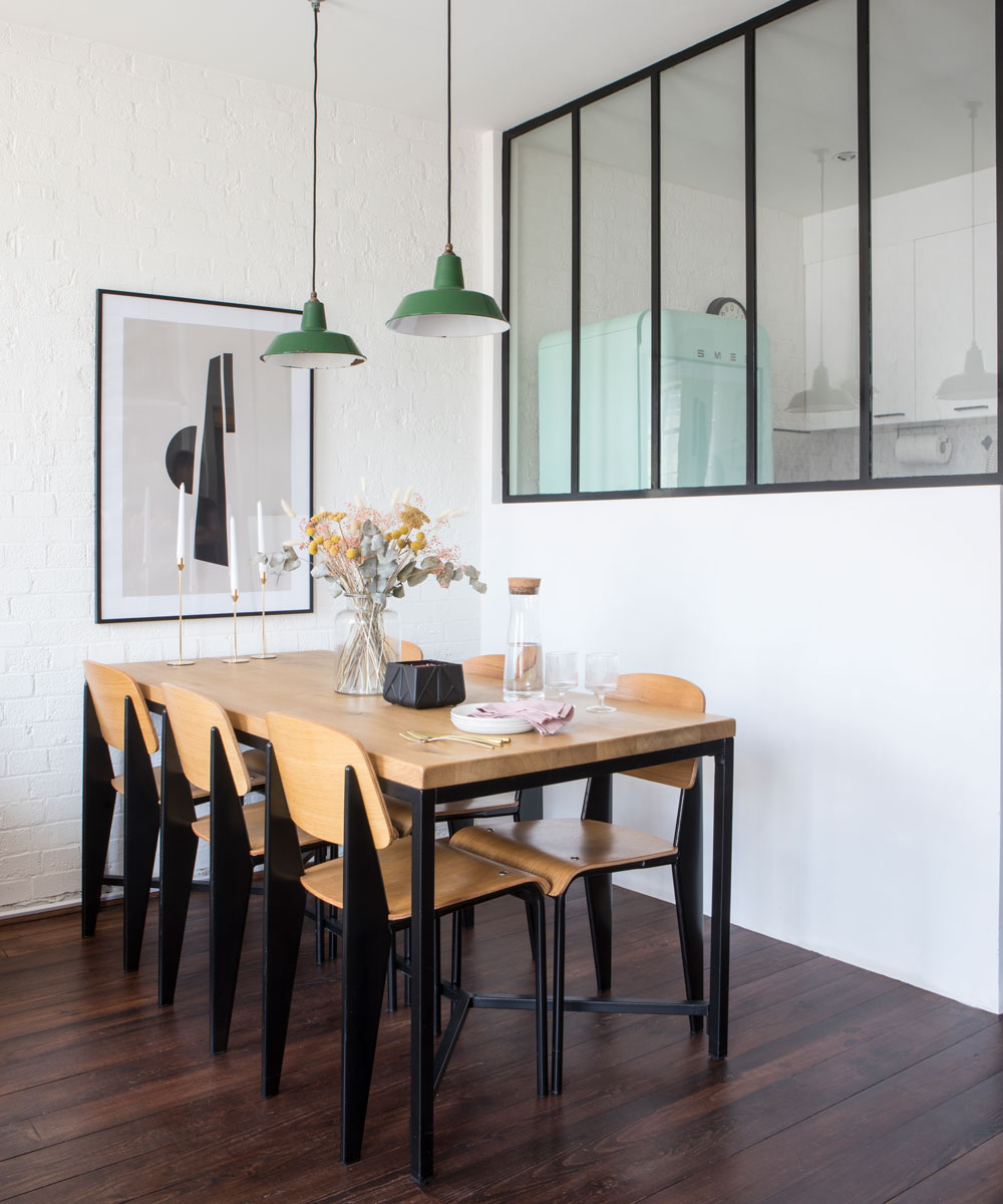 Dining area with wooden and steel table with 6 chairs on wooden floor with with windows facing the kitchen