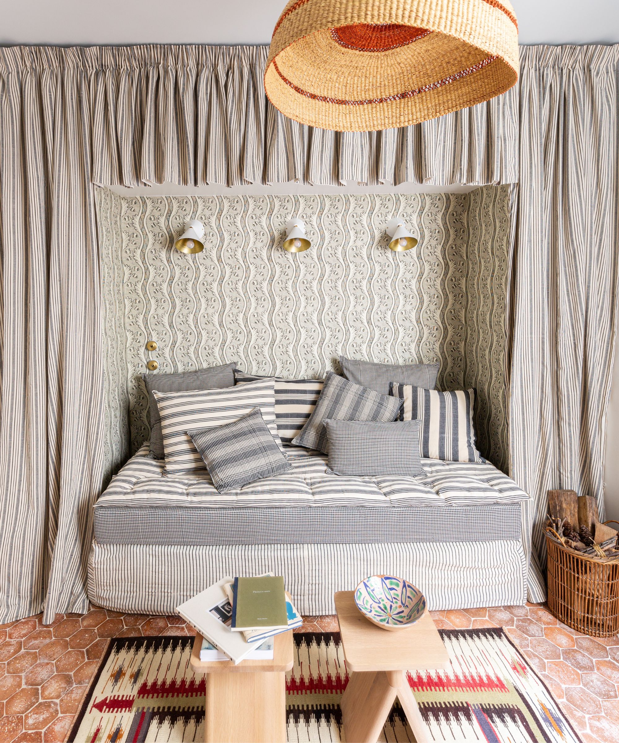 Living room with sofa bed and canopy, rattan light, tiled terracotta floor and wooden stools