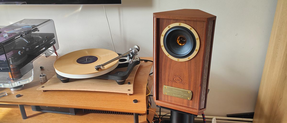 The Tannoy Autograph Mini pictured in a room next to a wooden sideboard and a record player