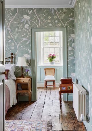 bedroom with green wallpaper and original wood flooring