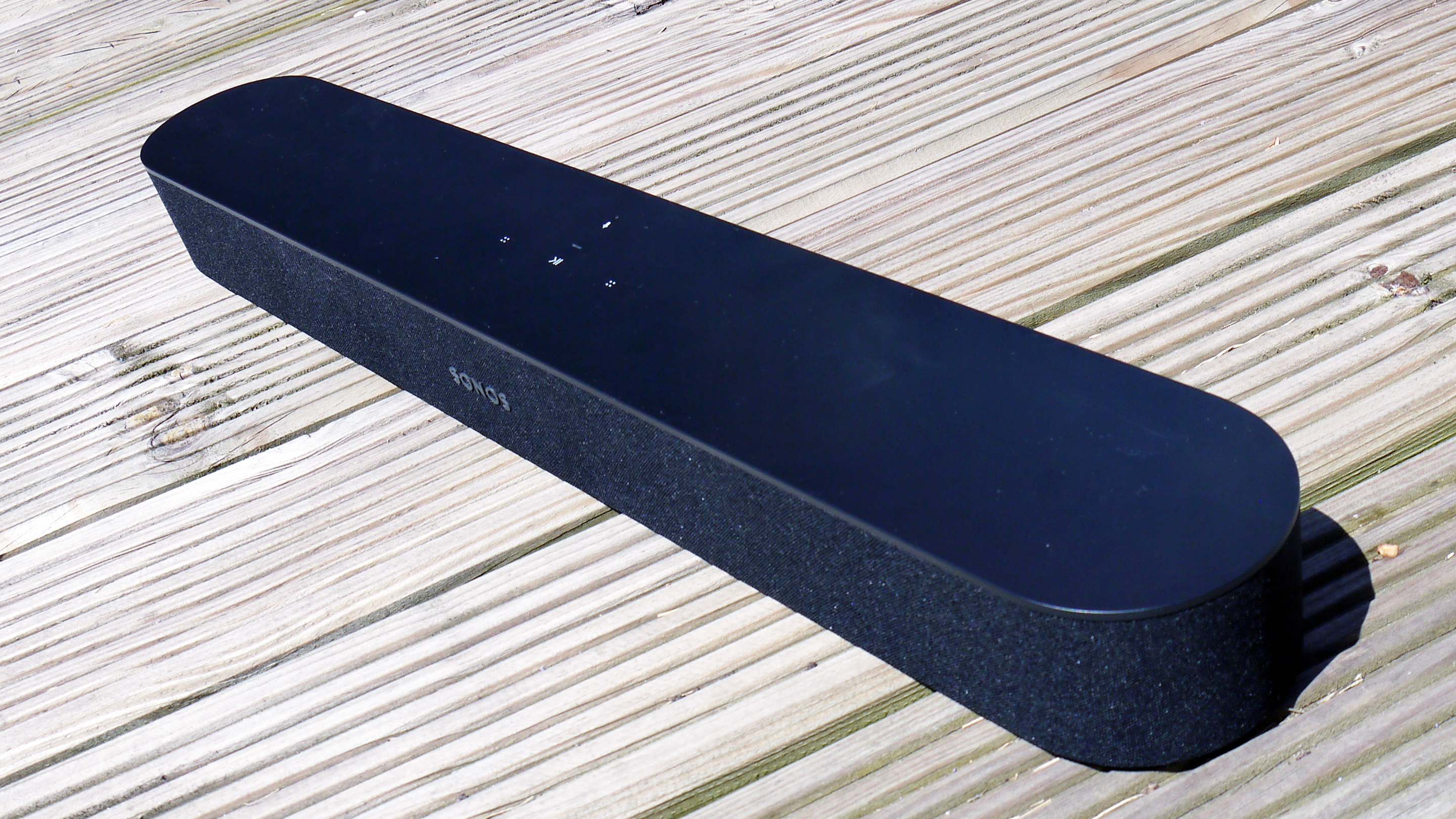 The Sonos балка черного цвета на деревянной палубе
