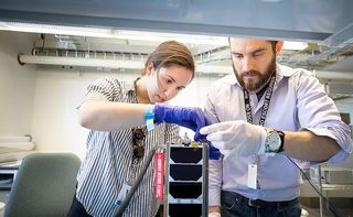 Analytical Space Inc. engineers Sera Evcimen (left) and Weston Marlow assemble the Meshbed satellite at MIT's Engine tech startup space before launch.