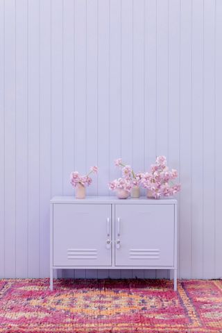 lilac panelled wall with lilac cabinet and pink pattered rug