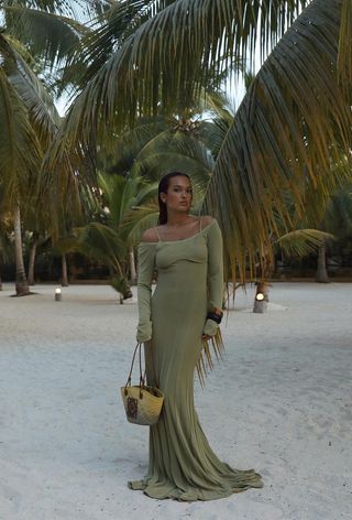 a photo of a woman's beach outfit with a green maxi dress and layered bangles and raffia bag