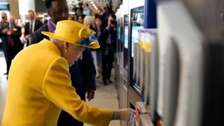 Queen Elizabeth II using a oyster card machine as she attends the Elizabeth line's official opening at Paddington Station on May 17, 2022 in London, England.
