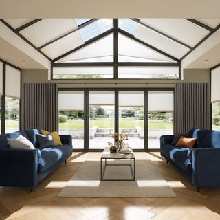 sunroom with herringbone parquet flooring blue sofas glass ceiling blinds
