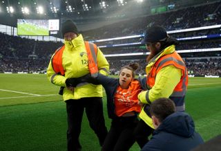 A protestor is removed by stewards during the Premier League match at the Tottenham Hotspur Stadium