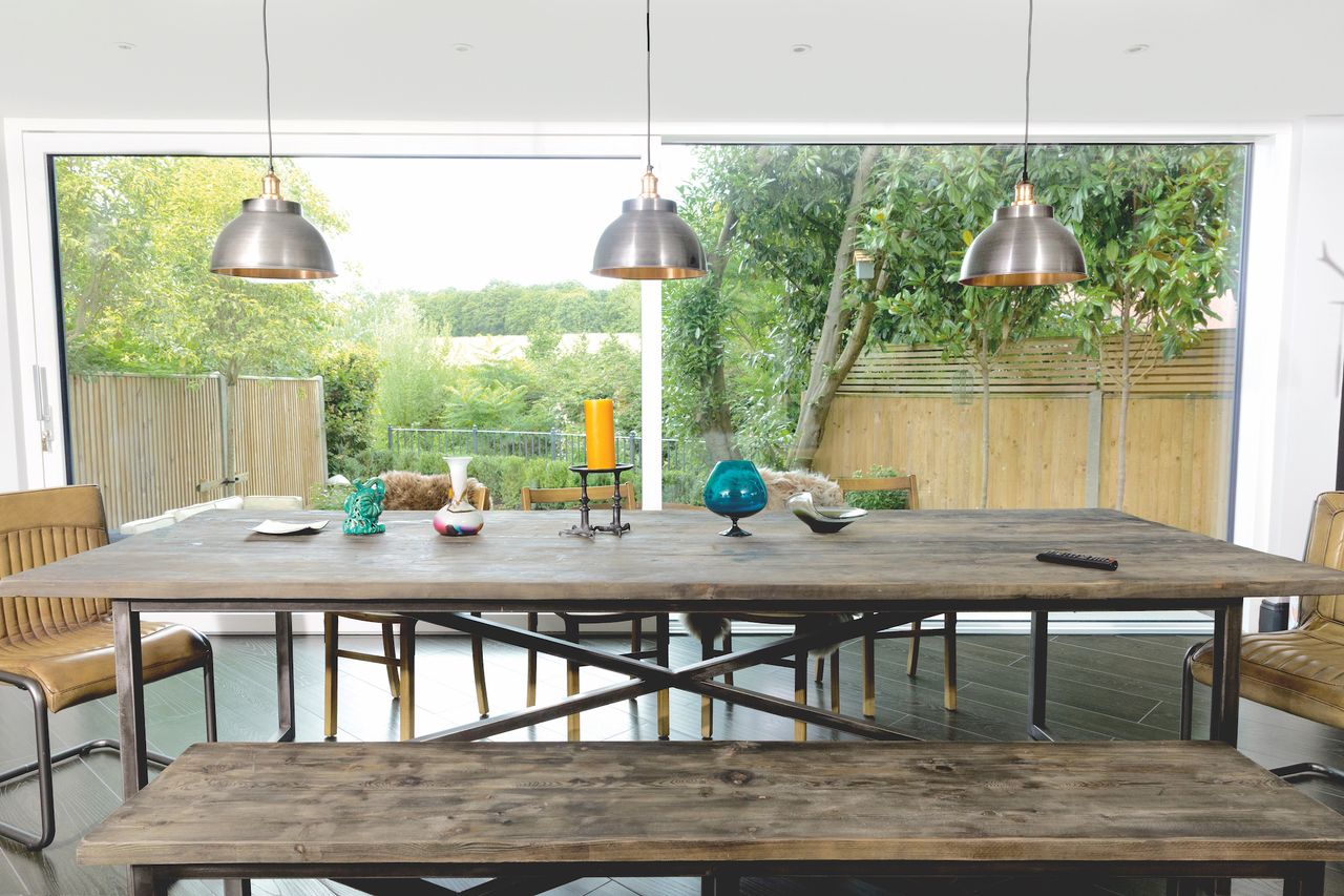 In front of the sliding doors which span the entire rear end, the dining space is dominated by an industrial-style table designed by Timothy Oulton using vintage reclaimed boat timber.