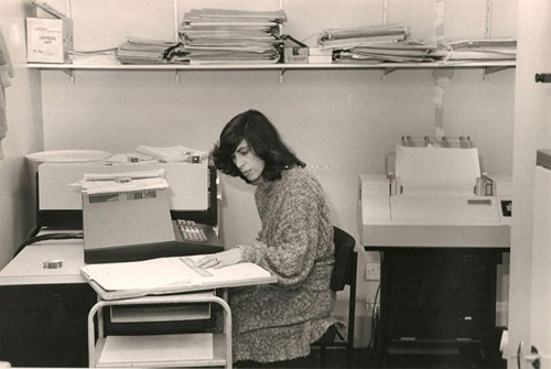 A woman sits at a computer in the 1980s
