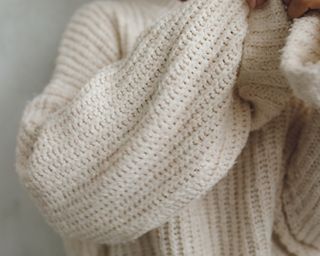 Close up of woman wearing cream wool chunky knit long-sleeved sweater