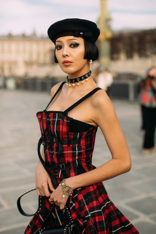 woman with a short bob, black hat, and red dress