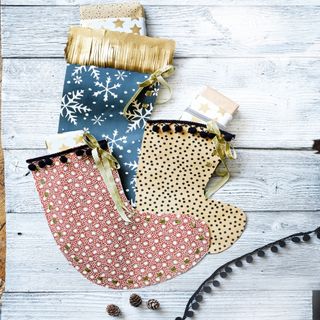 3 Christmas stockings with various patterns on a white washed floorboard