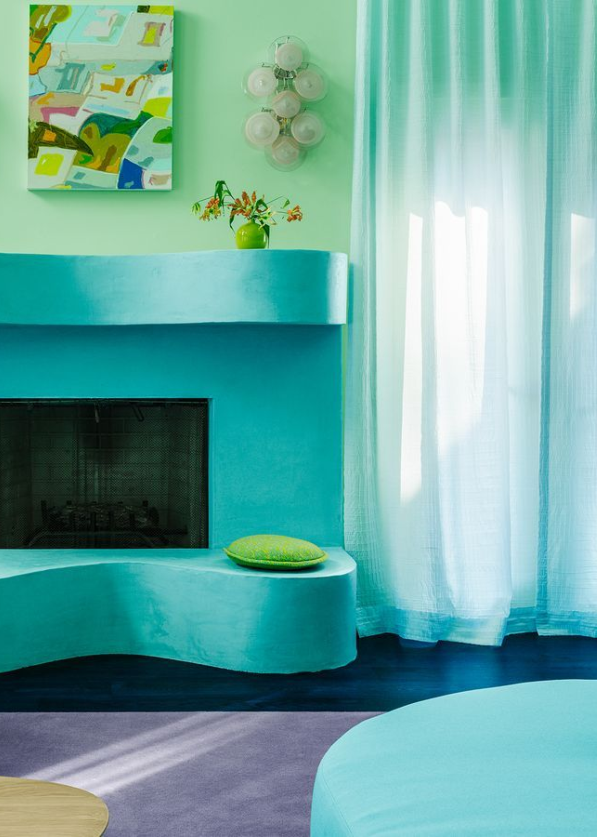 A living room with an aquamarine color scheme, and green and purple accents