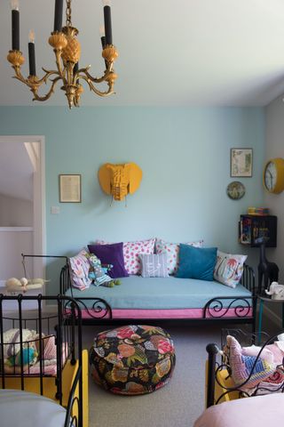 pale blue childrens room with children's beds, patterned pouffe and