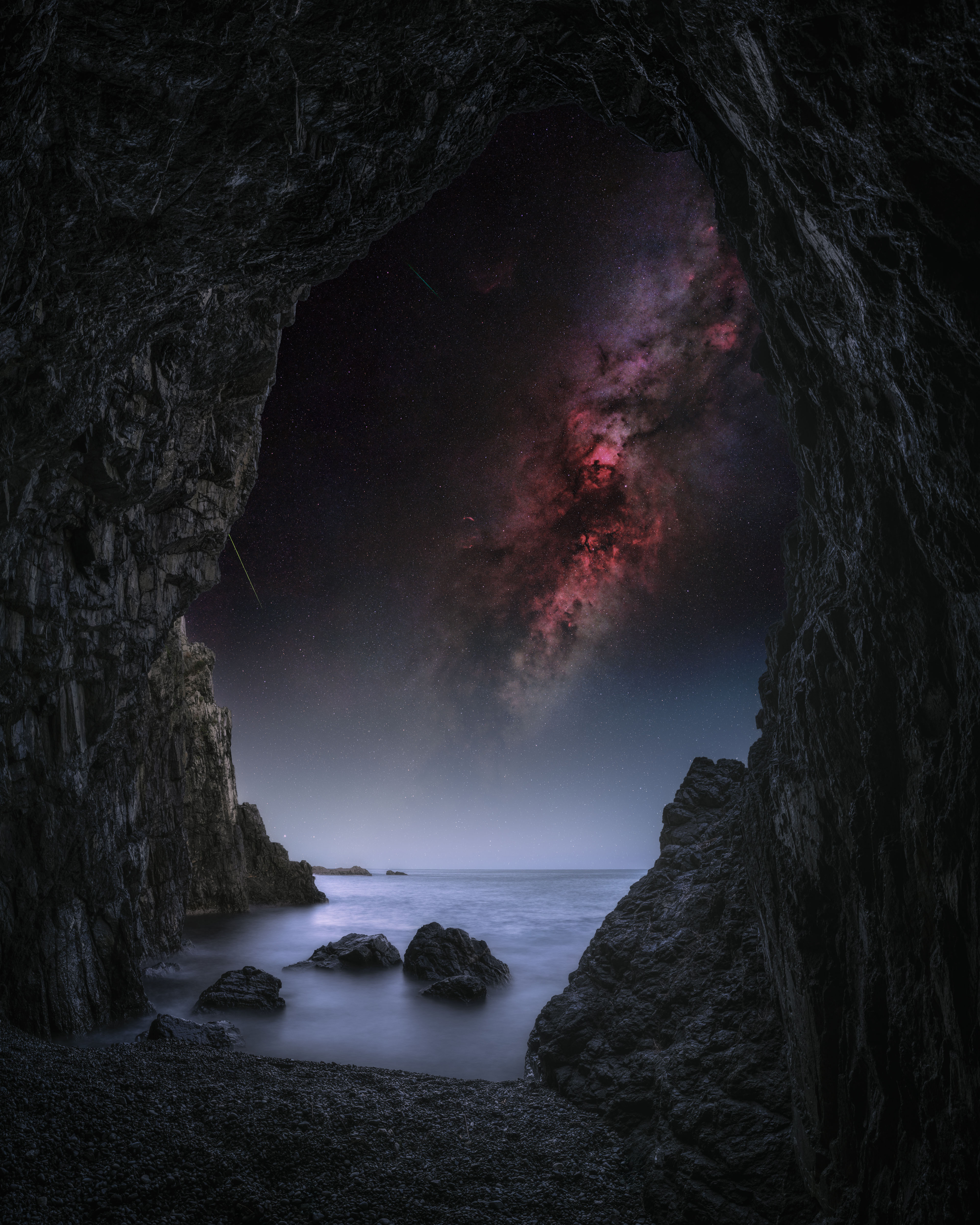 A night sky photograph from inside a cave looking at the Milky Way galaxy