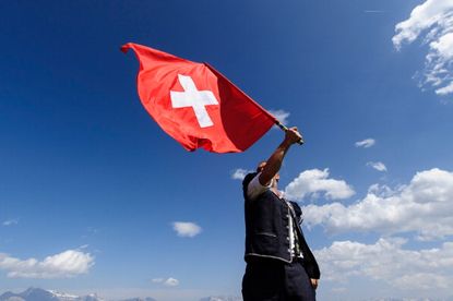 A man holds a Swiss flag.