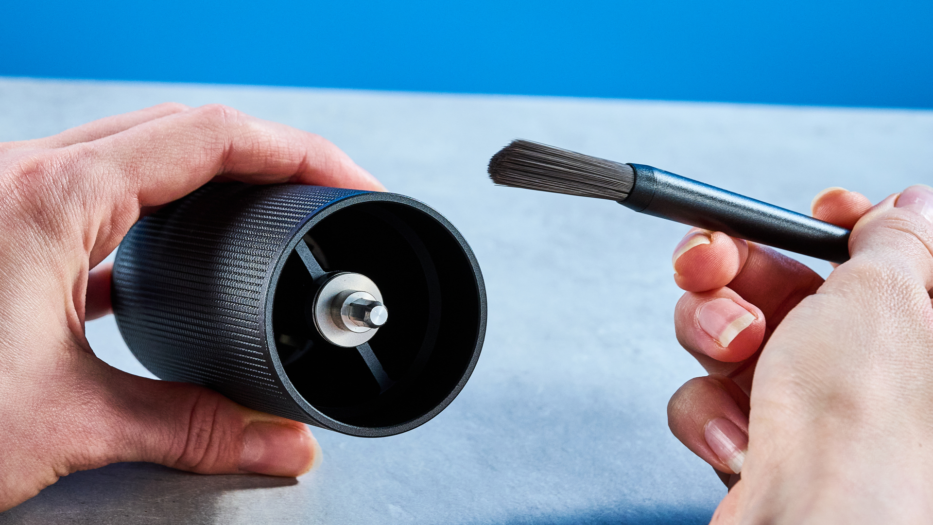the timemore chestnut c2s coffee grinder in black showing its hand crank and catch chamber photographed against the blue tom's guide background