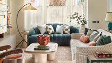 a living room with a teal colored croissant shaped sofa and a curved floor lamp