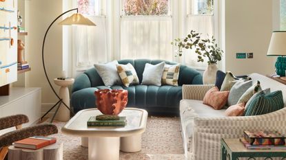 a living room with a teal colored croissant shaped sofa and a curved floor lamp