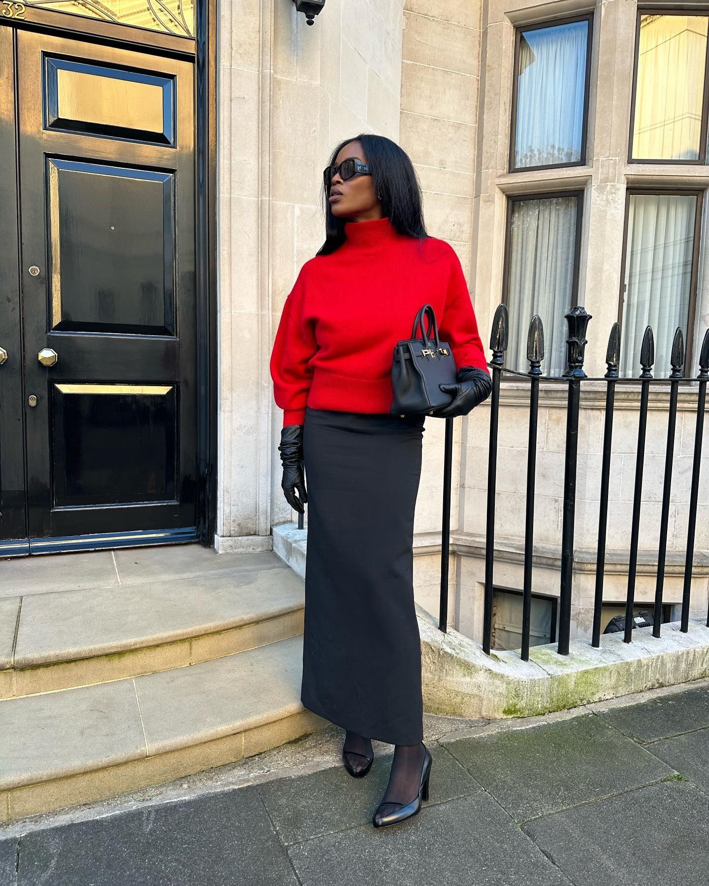 Influencer Marilyn wears a black column skirt, red turtleneck, black gloves, and black pumps.