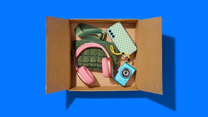 An open box with headphones, camera and other assorted items on a blue background.
